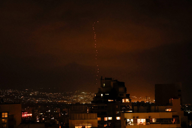 Pelacak dari senjata api yang ditembakkan ke udara untuk merayakan serangan rudal Iran ke Israel, terlihat di atas Beirut, Lebanon, Selasa (1/10/2024). Foto: Louisa Gouliamaki/REUTERS