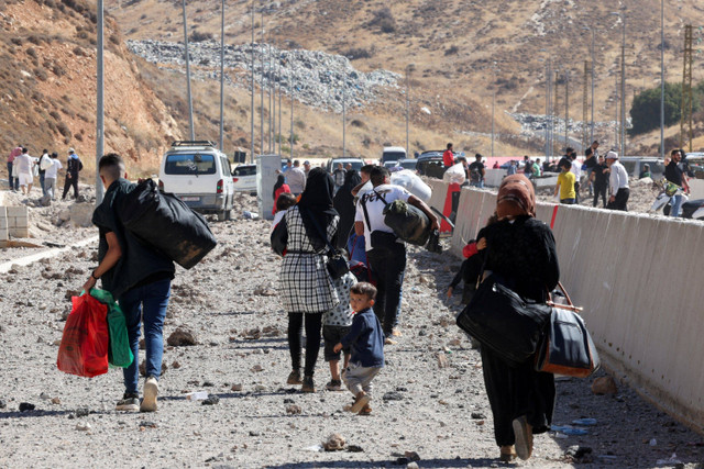 Warga berjalan melewati jalanan yang rusak imbas serangan Israel di perlintasan perbatasan Masnaa dengan Suriah, Lebanon, Jumat (4/10/2024). Foto: Mohamed Azakir/REUTERS 