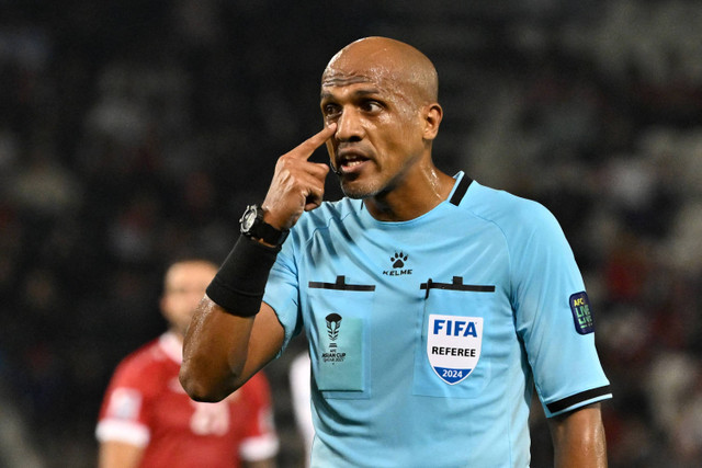 Wasit pertandingan Oman Ahmed al-Kaf memberi isyarat selama pertandingan sepak bola Grup B Piala Asia AFC Qatar 2023 antara Uzbekistan dan Suriah di Stadion Jassim bin Hamad di Doha pada 13 Januari 2024. Foto: HECTOR RETAMAL / AFP