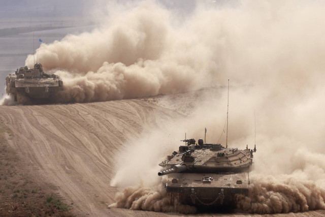 Tank-tank militer Israel melaju di sebuah area dekat perbatasan selatan Israel dengan Jalur Gaza, Minggu (6/10/2024). Foto: Menahem Kahana/AFP