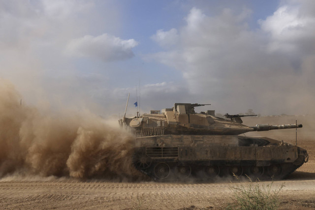 Sebuah tank militer Israel melaju di sebuah area dekat perbatasan selatan Israel dengan Jalur Gaza, Minggu (6/10/2024). Foto: Menahem Kahana/AFP