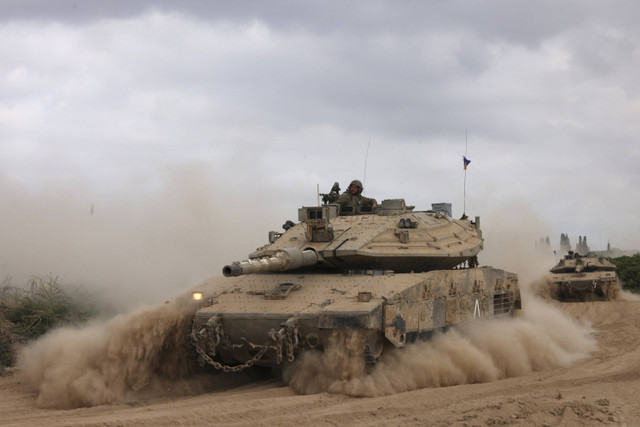 Sebuah tank militer Israel melaju di sebuah area dekat perbatasan selatan Israel dengan Jalur Gaza, Minggu (6/10/2024). Foto: Menahem Kahana/AFP