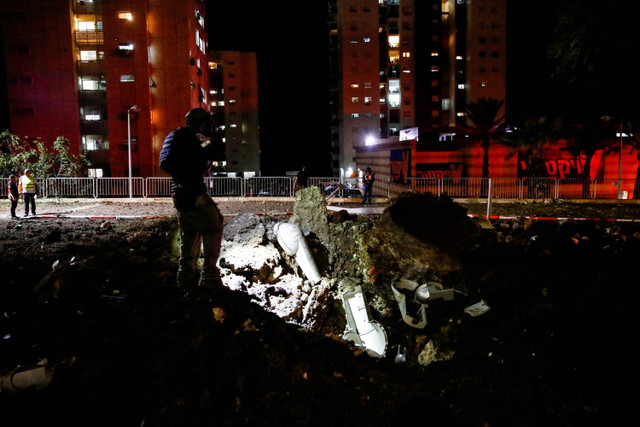 Anggota pasukan penyelamat Israel memeriksa lokasi jatuhnya proyektil di Haifa, Israel utara, Senin (7/10/2024). Foto: Shir Torem/REUTERS