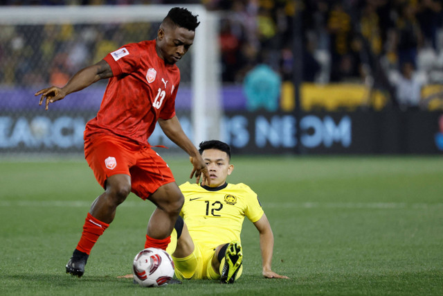 Pemain Timnas Bahrain Moses Atede (kiri) berebut bola dengan pemain Timnas Malaysia Arif Aiman pada pertandingan Grup E Piala Asia. Foto: Karim Jaafar / AFP