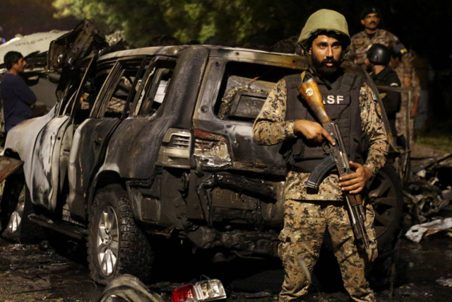 Anggota Pasukan Keamanan Bandara ASF berjaga di dekat reruntuhan kendaraan setelah ledakan di dekat Bandara Internasional Jinnah di Karachi, Pakistan, Minggu (6/10/2024). Foto: Shakil Adil/REUTERS