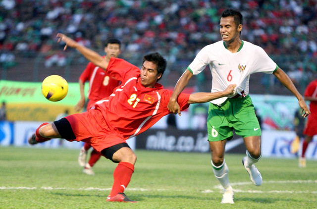 Nguyen Viet Thang (L#21) dari Vietnam berebut bola dengan Charis Yulianto (#6) dari Indonesia dalam pertandingan sepak bola persahabatan internasional di Surabaya pada tanggal 11 Juni 2008. Foto: Aziz Tio/AFP