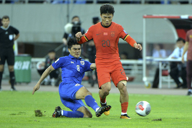 Xie Wenneng dari China berebut bola dengan Peeradon Chamratsamee dari Thailand dalam pertandingan sepak bola kualifikasi AFC Piala Dunia FIFA 2026 antara China dan Thailand di Shenyang di provinsi Liaoning, China timur laut (6/7/2024). Foto: STR / AFP / China OUT