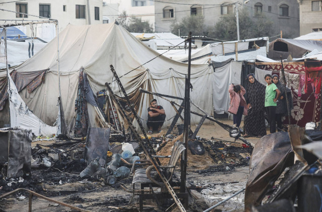 Warga Palestina mengamati kerusakan di lokasi serangan Israel terhadap tenda-tenda yang menampung para pengungsi, di tengah konflik Israel-Hamas, di rumah sakit Martir Al-Aqsa di Deir Al-Balah di Jalur Gaza tengah, Minggu (14/10/2024). Foto: Ramadan Abed/REUTERS