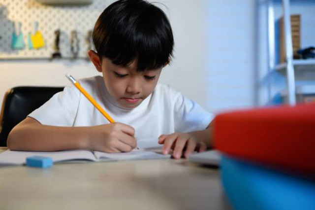 Ilustrasi anak laki-laki sedang menulis di buku. (Sumber: https://www.istockphoto.com).