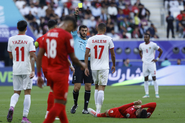 Wasit Emirat Omar Mohamed al-Ali memberikan kartu kuning kepada pemain Yordania Salem al-Ajalin pada pertandingan Grup E Piala Asia AFC Qatar 2023 antara Yordania dan Bahrain di Stadion Al-Janoub di Al-Wakrah, Doha (25/1/2024). Foto: KARIM JAAFAR/AFP