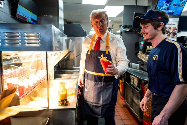 Calon presiden dari Partai Republik dan mantan Presiden AS Donald Trump bekerja di belakang meja kasir saat mengunjungi McDonalds di Feasterville-Trevose, Pennsylvania, Amerika Serikat, Minggu (20/10/2024). Foto: Doug Mills/Pool via REUTERS