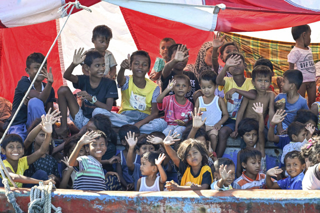 Anak-anak terlihat di atas kapal yang membawa pengungsi Rohingya saat berlabuh di lepas pantai Labuhan Haji di provinsi Aceh Selatan, Selasa (22/10/2024). Foto: Chaideer Mahyuddin/AFP