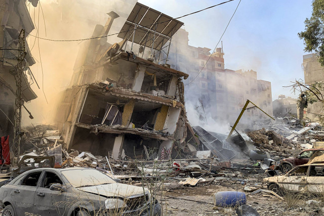 Asap mengepul dari bangunan dan kendaraan yang hancur dari lokasi serangan udara Israel pada hari sebelumnya di lingkungan Mreijeh di pinggiran selatan Beirut, Lebanon, Rabu (23/10/2024). Foto: AFP