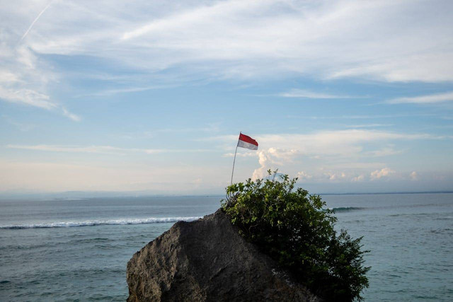 Ilustrasi Bendera Indonesi Berkibar di atas Batuan besar. (Sumber: https://www.pexels.com/id-id/).