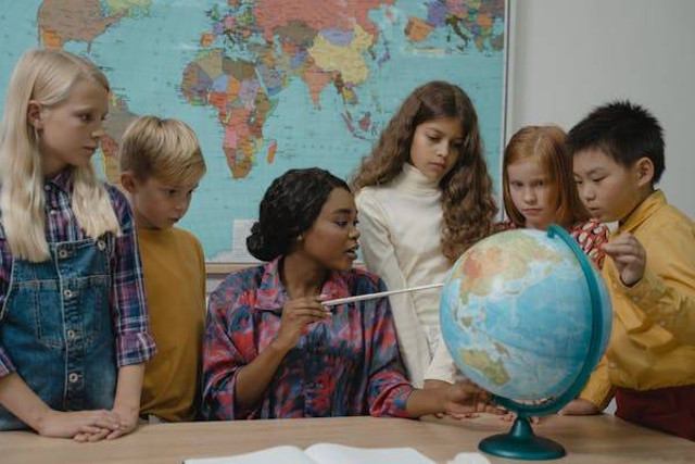 Ilustrasi Teacher teaching students about Geography using a Globe. Sumber: Pexels.com