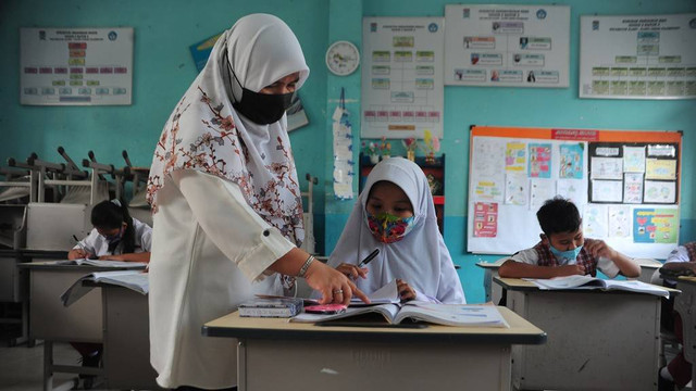 Guru membimbing siswa mengikuti Pembelajaran Tatap Muka (PTM) di ruang kelas Sekolah Dasar Negeri 153 Palembang, Sumatera Selatan, Selasa (8/2/2022). Foto: kumparan