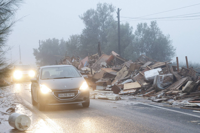 Mobil-mobil bergerak melewati barang-barang yang rusak dari sebuah pabrik mebel yang terkena dampak hujan lebat yang menyebabkan banjir di La Alcudia, wilayah Valencia, Spanyol, 30 Oktober 2024.  Foto: Jon Nazca/Reuters