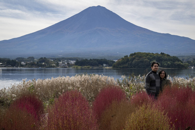 Orang-orang berfoto di depan Gunung Fuji, gunung tertinggi di Jepang dengan ketinggian 3.776 meter (12.460 kaki), di Fujikawaguchiko, prefektur Yamanashi pada tanggal 31 Oktober 2024. Foto: YUICHI YAMAZAKI/AFP