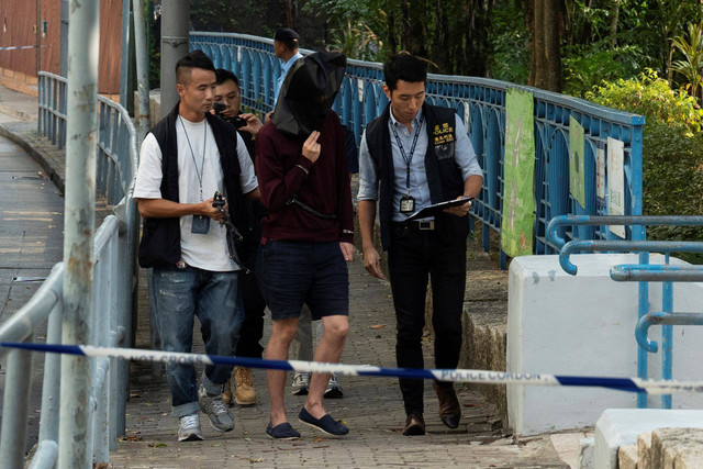 Polisi membawa tersangka untuk melakukan rekonstruksi pembunuhan WNI di sebuah air terjun di dalam taman di Hong Kong, Rabu (30/10/2024). Foto: Bertha Wang/AP Photo