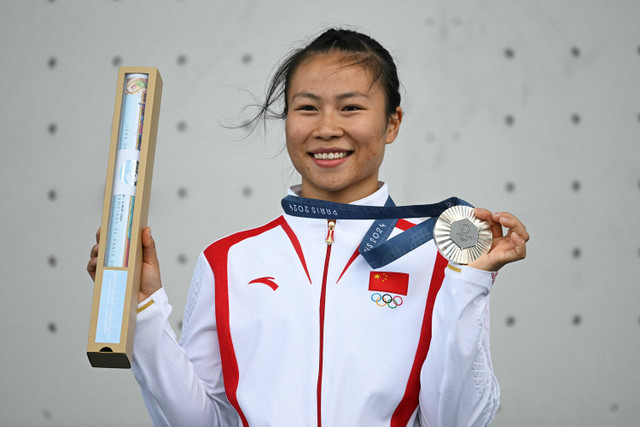 Peraih medali perak Deng Lijuan dari Tiongkok merayakan di podium saat upacara penyerahan medali kompetisi kecepatan olahraga panjat tebing putri pada Olimpiade Paris 2024 di Le Bourget Sport Climbing Venue di Le Bourget pada 7 Agustus 2024. Foto: Fabrice COFFRINI / AFP