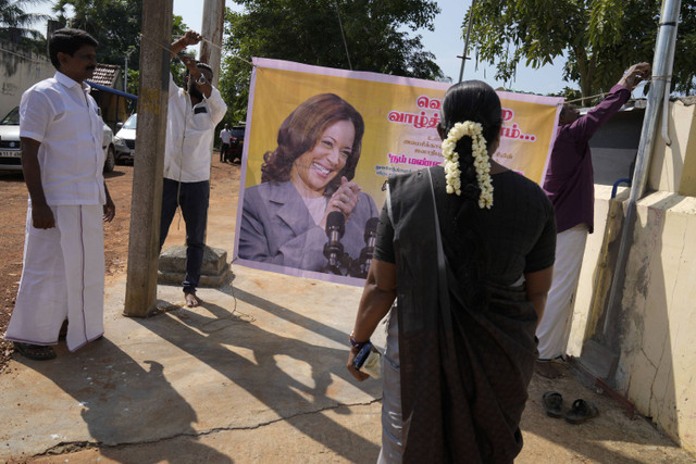 Penduduk desa mengikat spanduk yang menampilkan calon presiden dari Partai Demokrat, Wakil Presiden Kamala Harris, di luar kuil di Thulasendrapuram, desa leluhur Harris di negara bagian Tamil Nadu, India, Selasa (5/11/2024). Foto: Aijaz Rahi/AP Photo