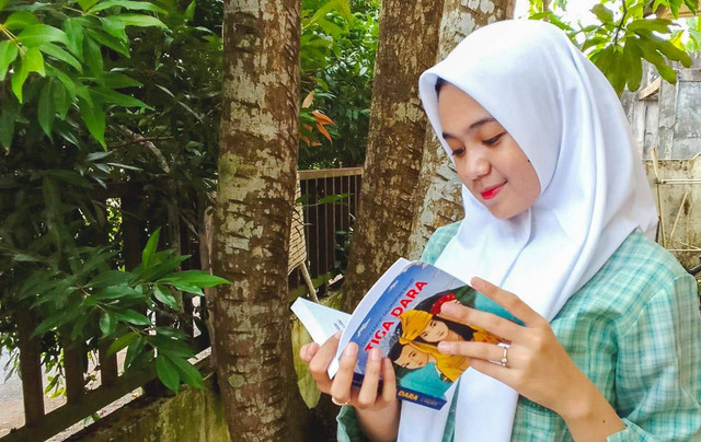 Seorang siswa sedang membaca buku cerita rakyat Kalbar 'Tiga Dara'. Foto: Dok. Indosat