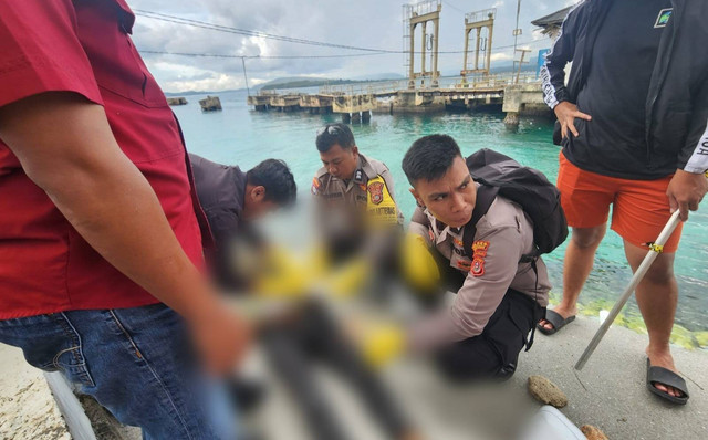 Polisi saat mengevakuasi mayat yang ditemukan terapung di laut.