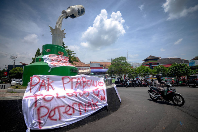 Pengendara melintas di dekat spanduk yang dipasang oleh peloper susu saat aksi mandi dan membuang susu di Tugu Susu Tumpah, Boyolali, Jawa Tengah, Sabtu (9/11/2024). Foto: Aloysius Jarot Nugroho/ANTARA FOTO  