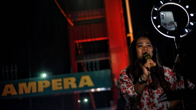 Aksi pengamen daring menggelar live medsos di atas Jembatan Ampera Palembang, Minggu (10/11) Foto: ary peiyanto/urban id