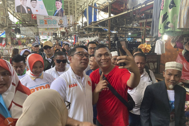 Calon Gubernur DKI Jakarta nomor urut satu Ridwan Kamil berswafoto dengan warga saat blusukan di Pasar Muara Angke, Jakarta Utara, Rabu (13/11/2024).  Foto: Alya Zahra/kumparan 