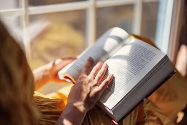 A woman reading a book by the window. Photo by https://www.istockphoto.com/id/portfolio/Imgorthand?mediatype=photography