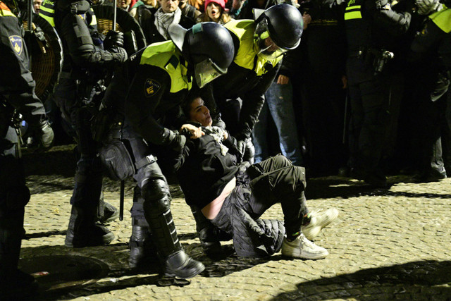 Petugas polisi menahan seorang pengunjuk rasa dalam sebuah demonstrasi pro-Palestina yang tidak sah di Dam Square di Amsterdam, Belanda, Rabu (13/11/2024) waktu setempat. Foto: NICK GAMMON/AFP