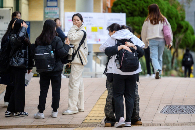 Siswa berpelukan saat tiba jelang mengikuti Ujian Kemampuan Skolastik Perguruan Tinggi tahunan yang dikenal secara lokal sebagai Suneung di Yeouido Girls High School, Seoul, Korea Selatan, Kamis (14/11/2024). Foto: ANTHONY WALLACE / AFP