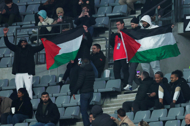 Seorang penggemar mengibarkan bendera Palestina saat menghadiri pertandingan Prancis melawan Israel pada laga lanjutan UEFA Nations League di Stade de France, Saint-Denis, Prancis, Kamis (14/11/2024). Foto: Gonzalo Fuentes/REUTERS 