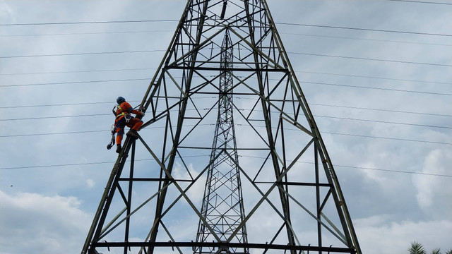 Salah satu anggota dari tim Pemeliharaan dan Pekerjaan Dalam Keadaan Bertegangan (PDKB) PLN sedang memanjat tower untuk melakukan pemeliharaan benang layangan. Foto: Alycia Tracy Nabila/Hi!Pontianak