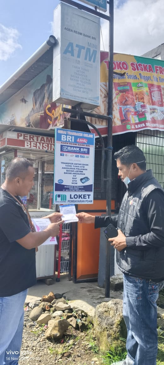 Pemilik AgenBRILink di Desa Sentral Baru, Kecamatan Bermani Ulu, Kabupaten Rejang, Bengkulu, Riswan Nurhadi (kiri) dalam membantu masyarakat mendapatkan layanan perbankan. Foto: Dok. BRI