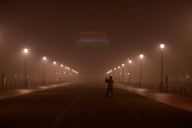 Seorang pria menyapu jalan saat langit diselimuti kabut asap akibat polusi udara yang mengkhawatirkan, di New Delhi, India, Minggu (17/11/2024). Foto: Anushree Fadnavis/ REUTERS