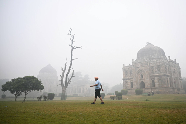 Warga berolahraga saat langit diselimuti kabut asap akibat polusi udara di taman Lodhi, New Delhi, India, Senin (18/11/2024). Foto: Money SHARMA / AFP