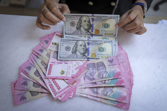 Seorang petugas menunjukan pecahan Dolar AS dan Rupiah di kawasan Kwitang, Jakarta, Senin (18/11/2024). Foto: Iqbal Firdaus/kumparan