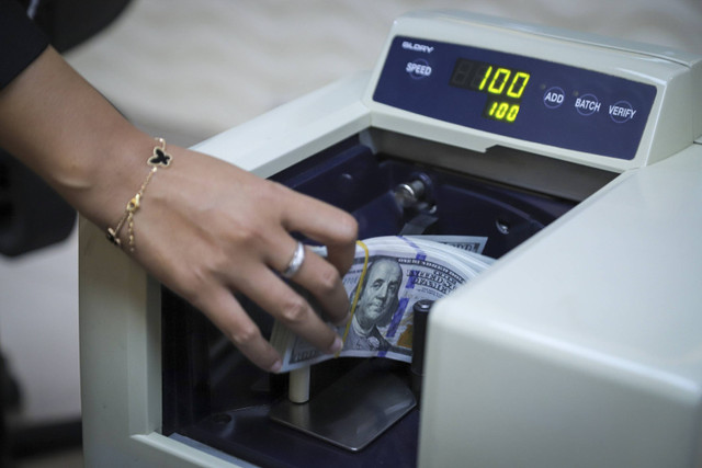 Seorang petugas menghitung pecahan Dolar AS dan Rupiah di kawasan Kwitang, Jakarta, Senin (18/11/2024). Foto: Iqbal Firdaus/kumparan