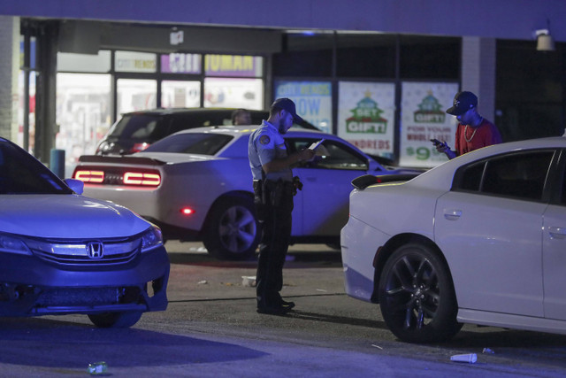 Seorang petugas polisi New Orleans mengambil laporan di tempat kejadian di tempat parkir Save O Lot di mana beberapa orang ditembak dan terbunuh di New Orleans, Minggu (17/11/2024). Foto: David Grunfeld/The New Orleans Advocate via AP