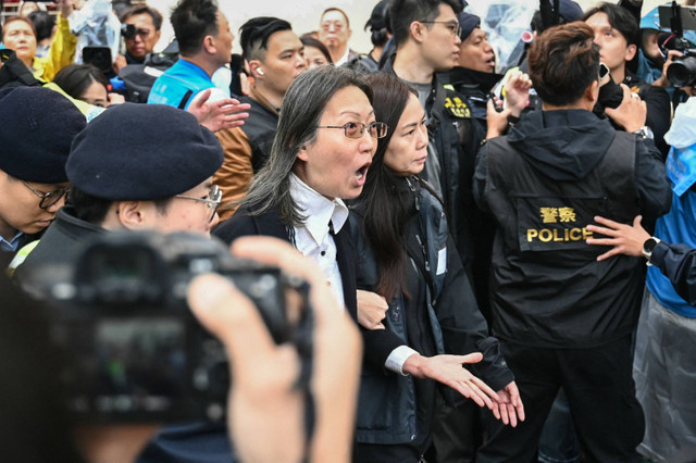 Polisi menahan seorang wanita (tengah) di luar Pengadilan Magistrat Kowloon Barat di Hong Kong, Selasa (19/11/2024). Foto: PETER PARKS / AFP