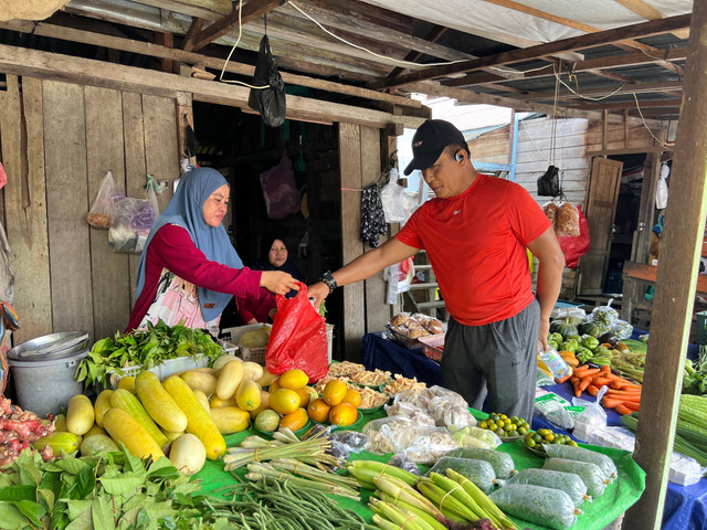 Didi Haryono saat membeli sayur dari pedagang di Pasar Pagi Putussibau. Foto: Yulia Ramadhiyanti/Hi!Pontianak