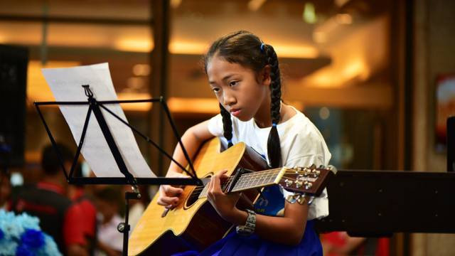 Seorang wanita bermain gitar. Foto: meesilpa sornsing/Shutterstock.