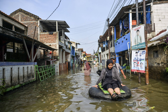 Warga menggunakan perahu karet untuk menuju rumah saat banjir melanda Kampung Bojongasih, Dayeuhkolot, Kabupaten Bandung, Jawa Barat, Minggu (24/11/2024). Foto: Raisan Al Farisi/ANTARA FOTO