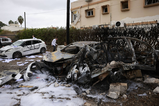 Warga memeriksa kerusakan setelah roket ditembakkan dari Lebanon, di Petah Tikva dekat Tel Aviv, Minggu (24/11/2024). Foto: Menahem Kahana/AFP