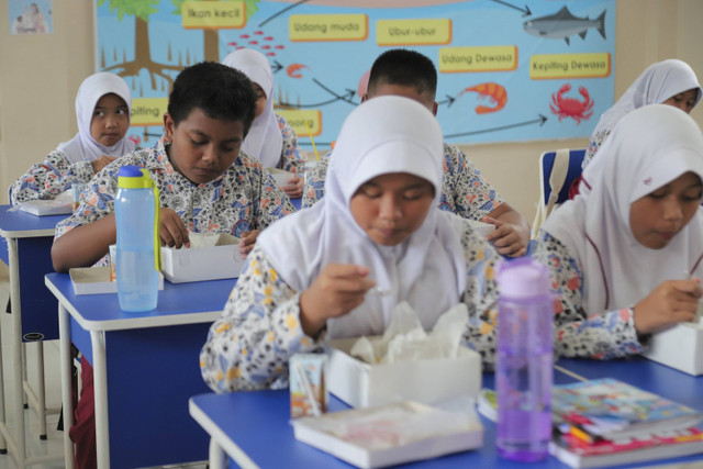 Sejumlah siswa menyantap makanan saat simulasi program Makan Siang Bergizi Gratis di sekolah wilayah Lanud Halim Perdanakusuma di SDS Angkasa 5 Lanud Halim Perdanakusuma, Jakarta, Selasa (26/11/2024). Foto: Iqbal Firdaus/kumparan