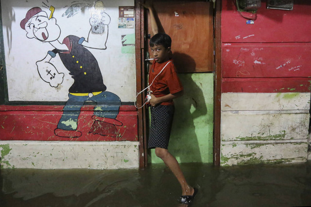 Seorang anak berada di depan rumahnya saat banjir rob di kawasan Muara Angke, Jakarta, Senin (18/11/2024). Foto: Alif Bintang/ANTARA FOTO