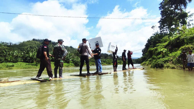 Anggota KPPS TPS 14 Desa Muaracikadu, Kabupaten Cianjur, membawa logistik pilkada menggunakan rakit bambu, Selasa (26/11/2024). Foto: Dok. Istimewa