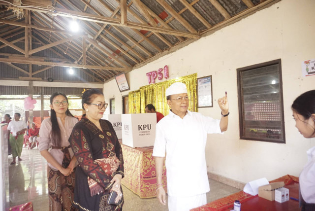 Cagub Bali nomor urut 01 Wayan Koster bersama istri Ni Luh Putu Putri Suastini dan anak kedua bernama Ni Made Wibhuti Bhawani di TPS 01, Desa Sembiran, Kabupaten Buleleng, Bali, Rabu (27/11/2024). Foto: Denita BR Matondang/kumparan